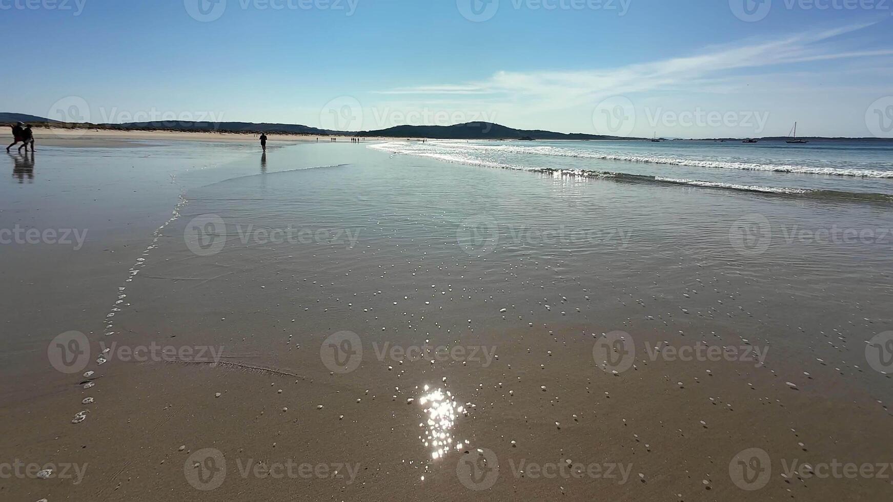 A serene beach with shimmering blue water and gentle footprints in warm sand, perfect for relaxation photo
