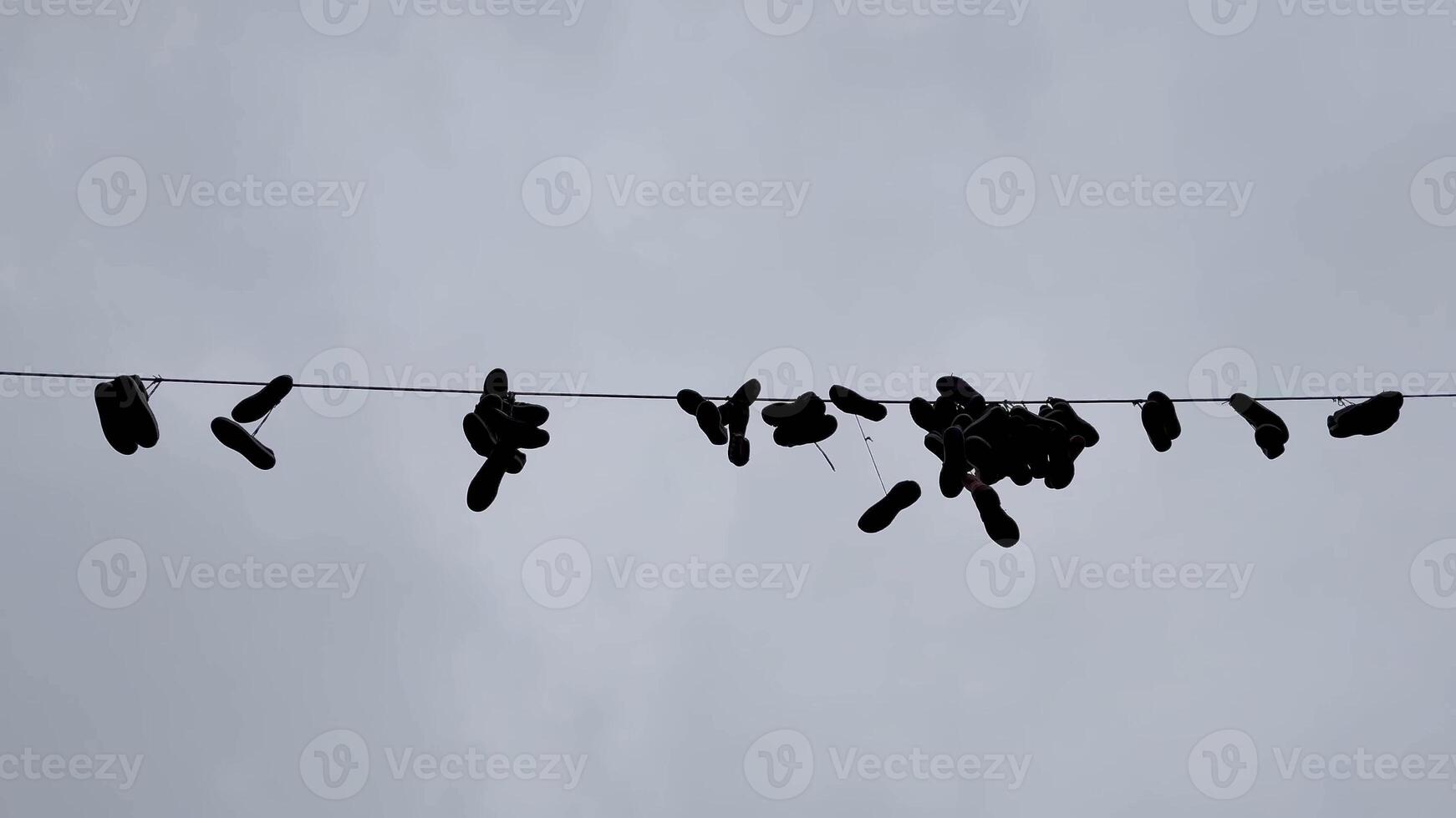 A creative and artistic display of sneakers hanging from a power line amidst a cloudy and dramatic sky photo
