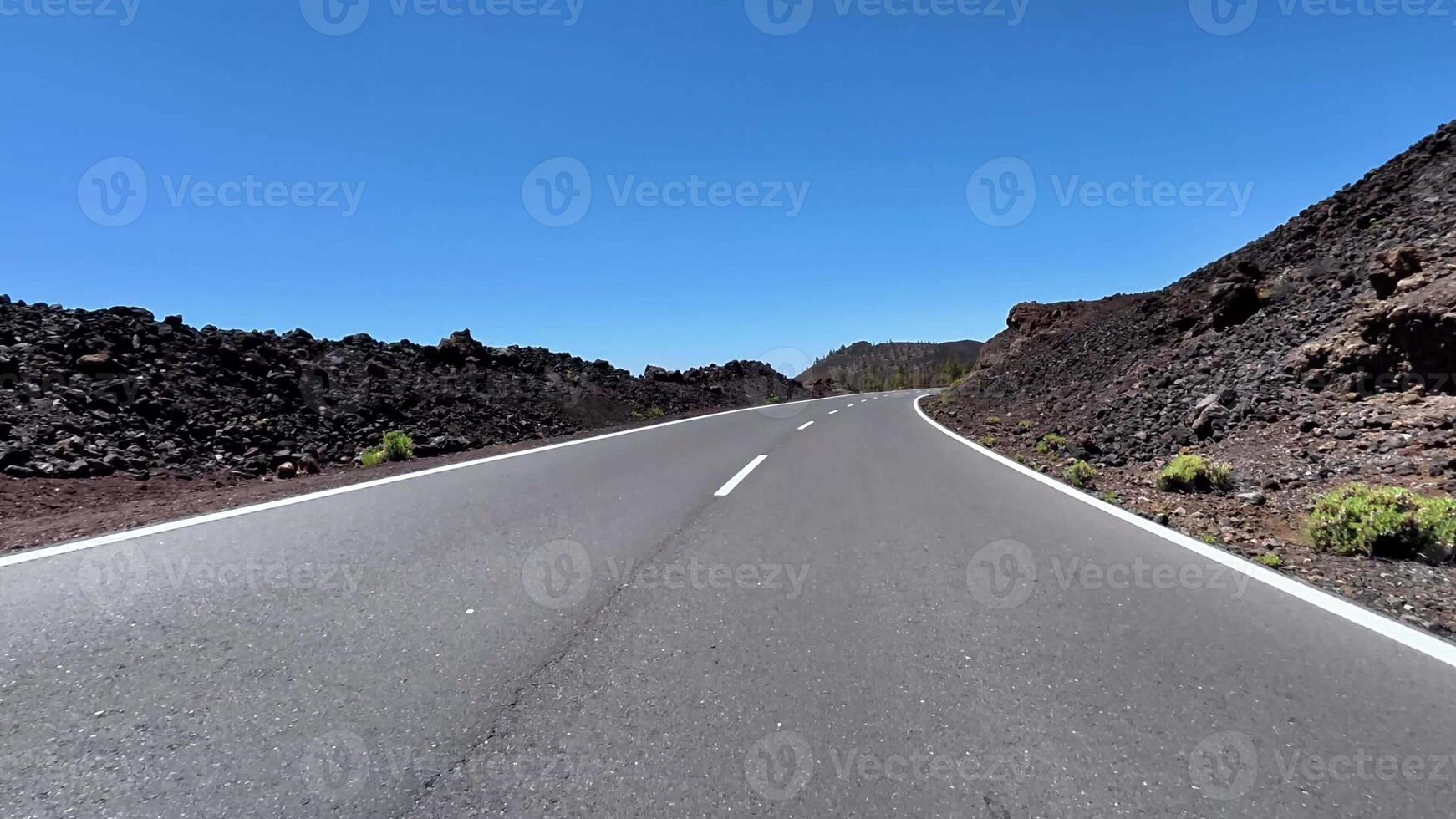 A picturesque winding road meanders through stunning volcanic terrain beneath a beautifully clear blue sky photo