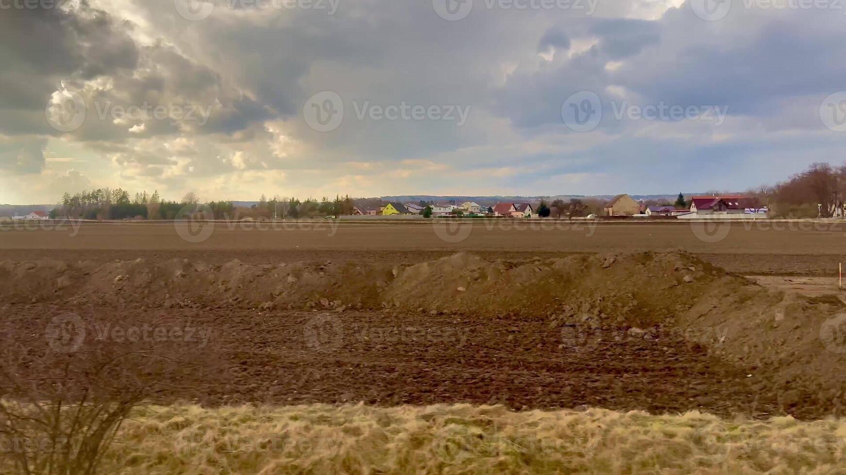 A beautifully picturesque rural scene showcasing charming homes and freshly plowed fields beneath a cloudy sky photo