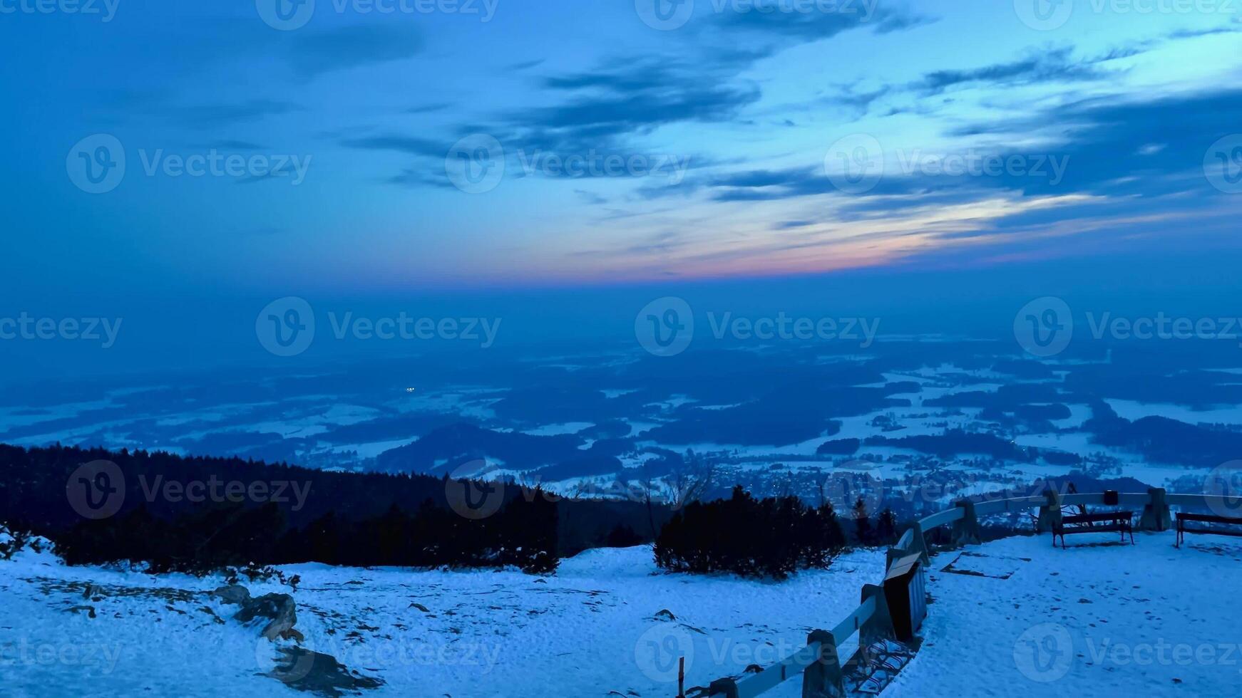 Evening view of snow-capped mountains and bright sky at sunset from an observation deck on top of a mountain. High quality 4k footage photo