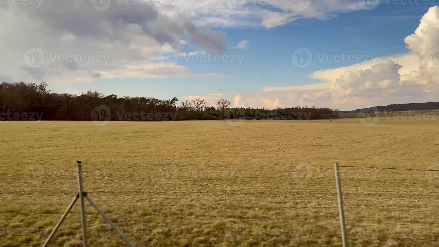 A serene and peaceful view showcasing expansive fields under a bright blue sky dotted with fluffy, scattered clouds photo
