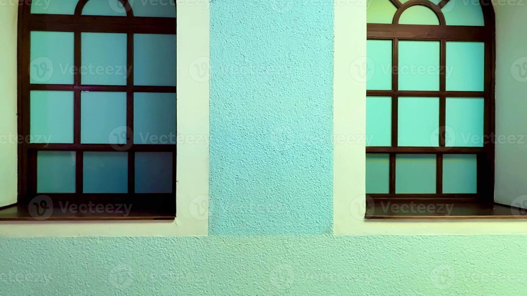 An aesthetically pleasing image showcasing two stunning windows alongside a classic clock on a vibrant blue wall photo