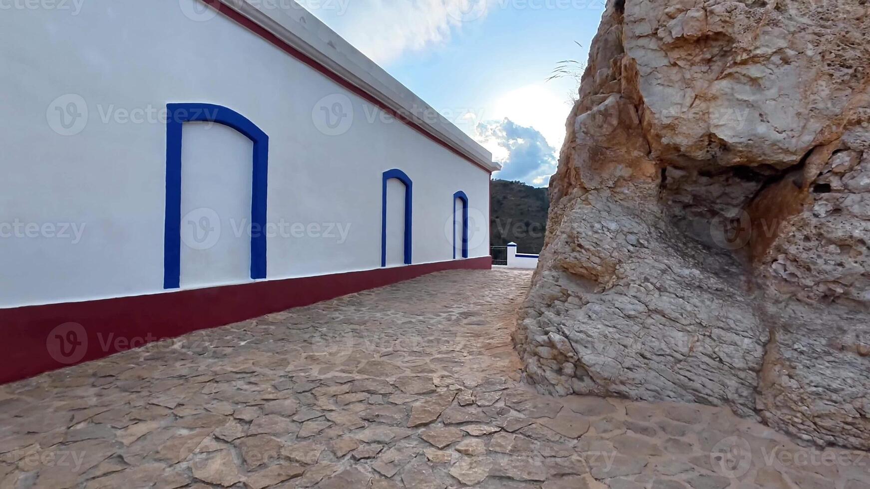 Stroll a charming stone pathway by a cliff, showcasing vibrant architecture and stunning panoramic views photo