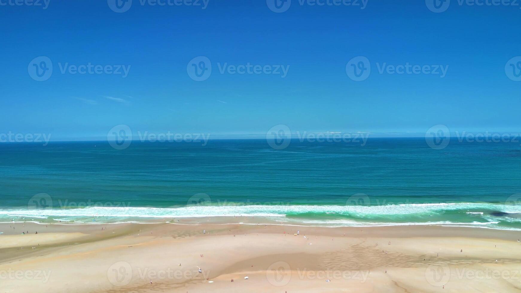 A breathtaking view of a tranquil beach depicting calm waves gently lapping against the shore and a vibrant azure sky photo
