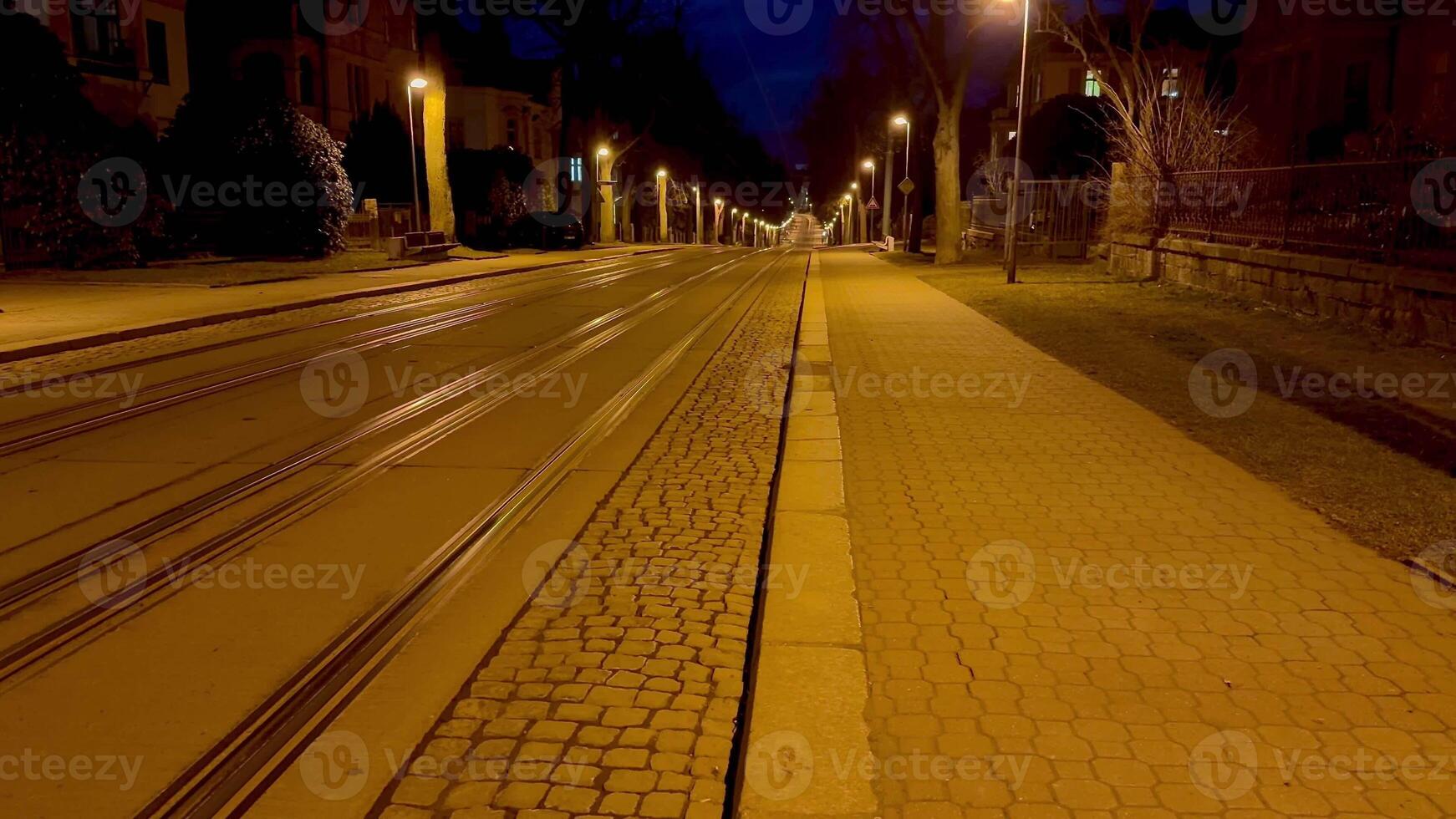 The empty city tram tracks, bathed in the warm glow of streetlights, create a serene atmosphere at night photo