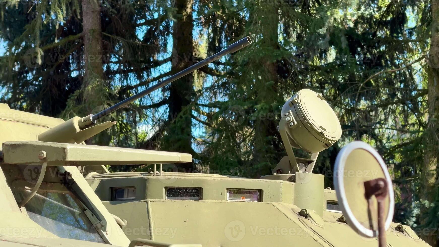 A closeup view of a military armored vehicle shows its turret and unique camouflage for concealment in a forest photo