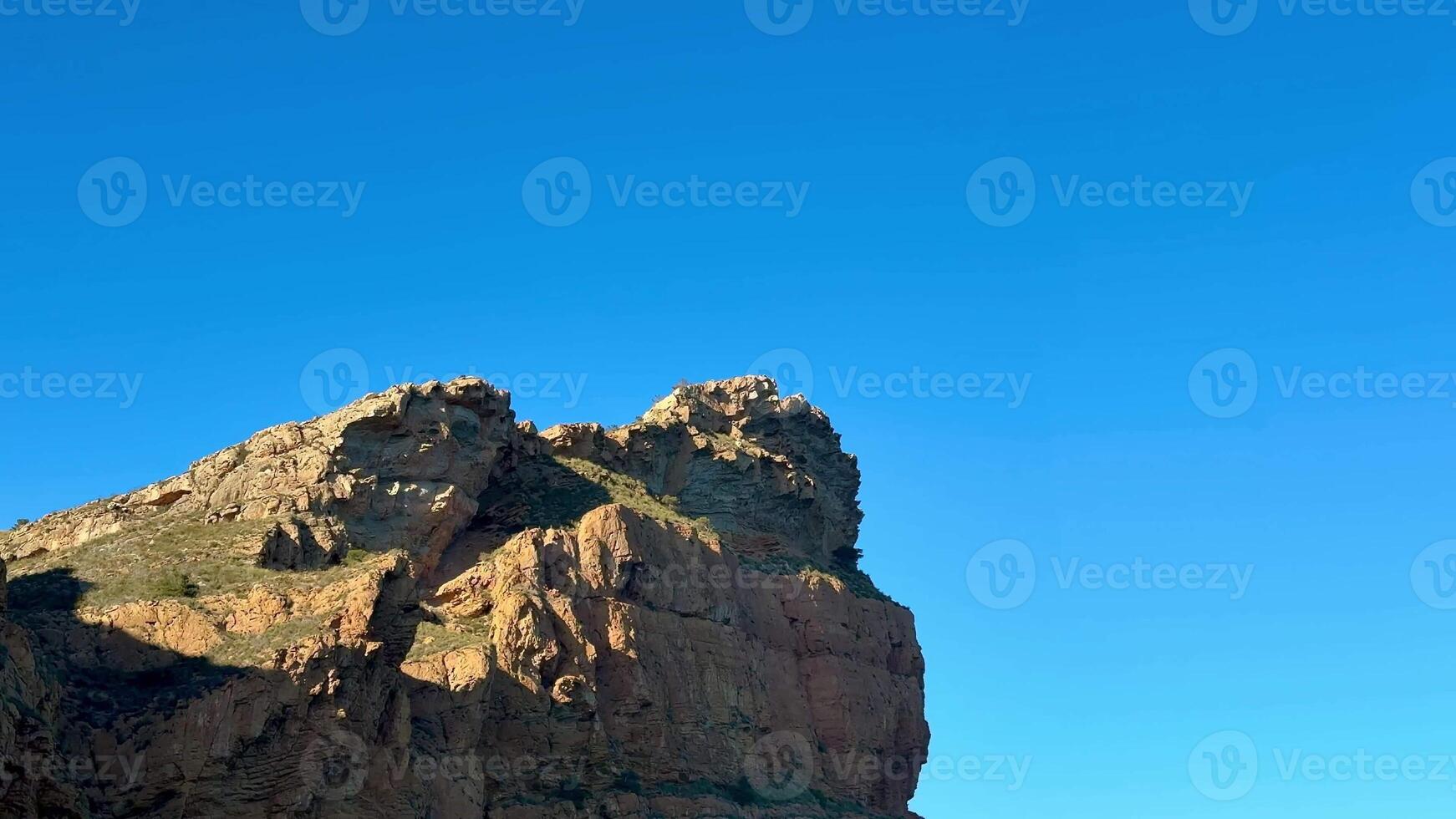 The captivating rocky shoreline features clear blue skies and calm waters, making it perfect for nature enthusiasts photo