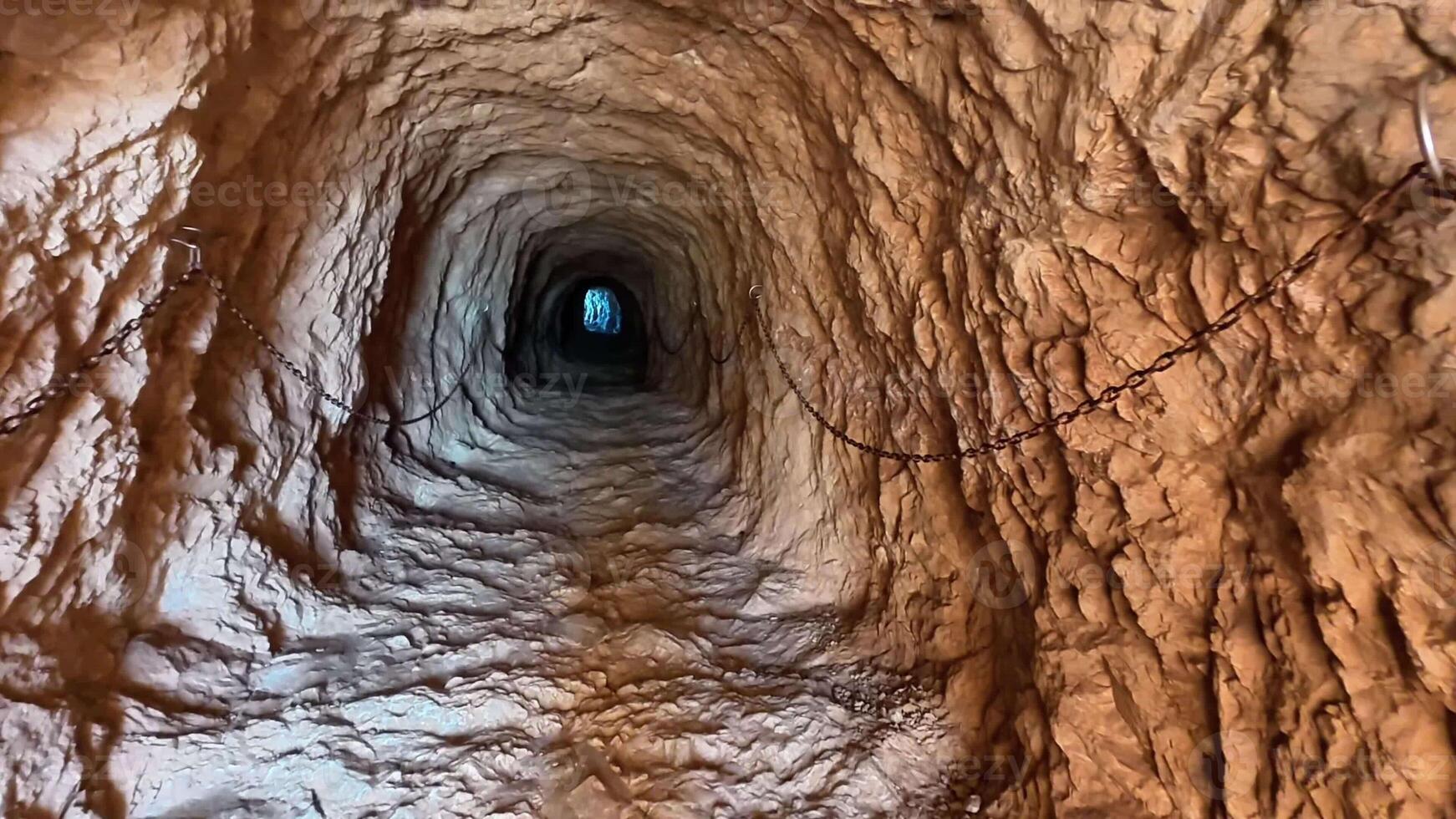 Explore a captivating tunnel that leads to a bright light, showcasing intriguing textures and depth. photo