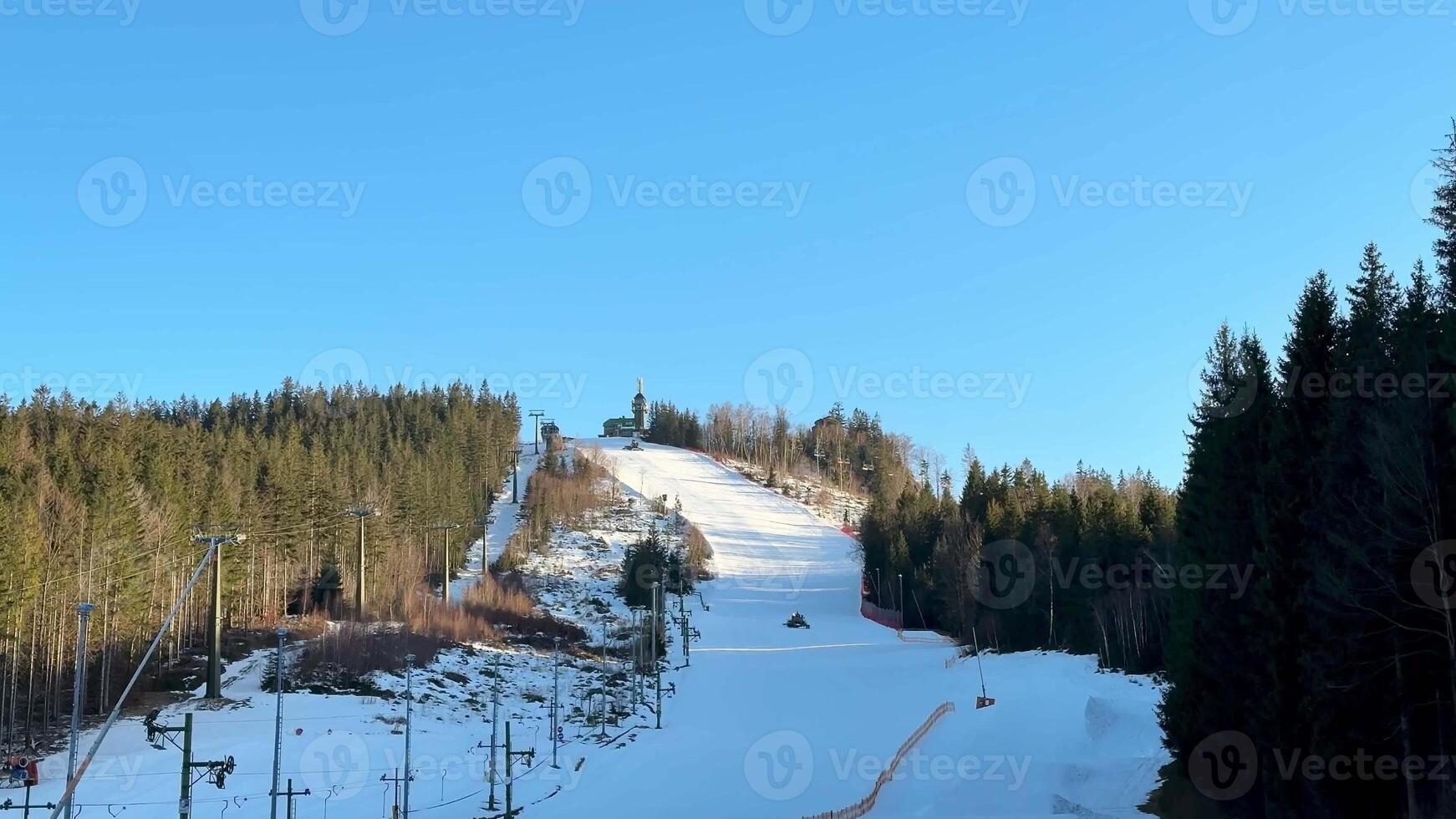 Beautiful snowy ski slope with trees on a clear blue sky day, perfect for winter sports enthusiasts. photo