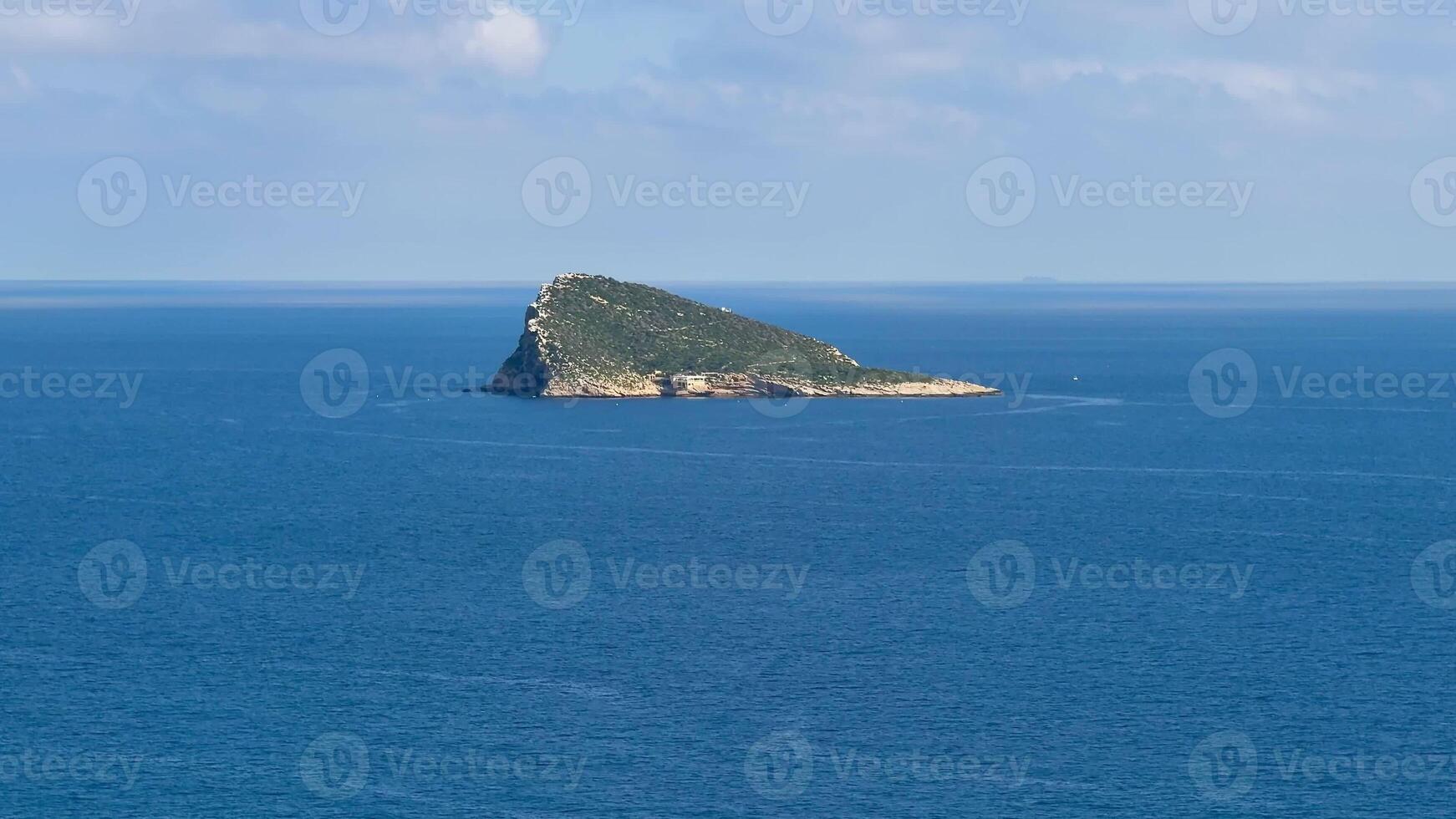 A stunning and beautiful island gracefully rising from the tranquil and serene blue waters beneath a clear sky photo