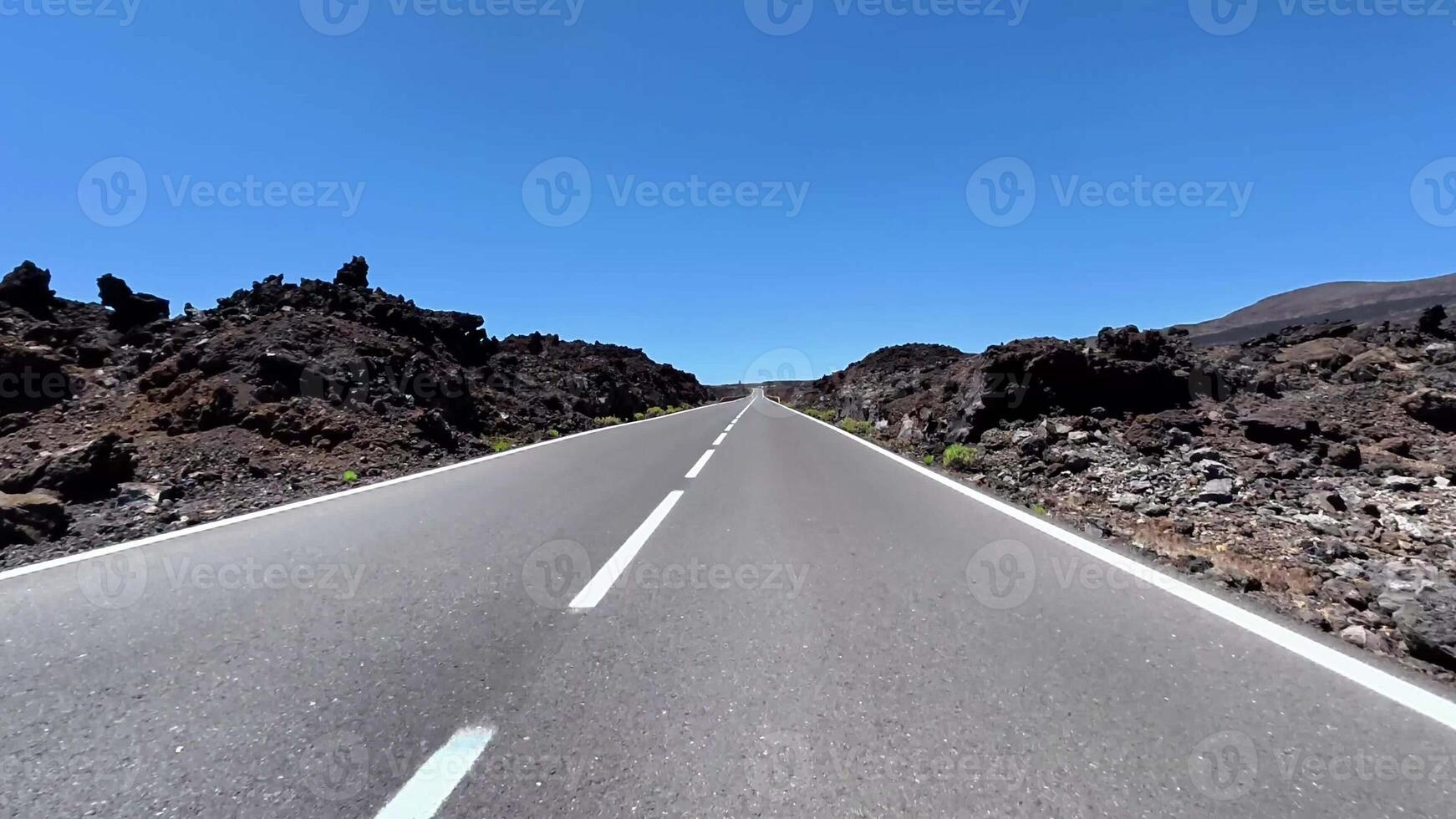 The stunning view of a straight road through volcanic rock formations under a clear blue sky is captivating photo
