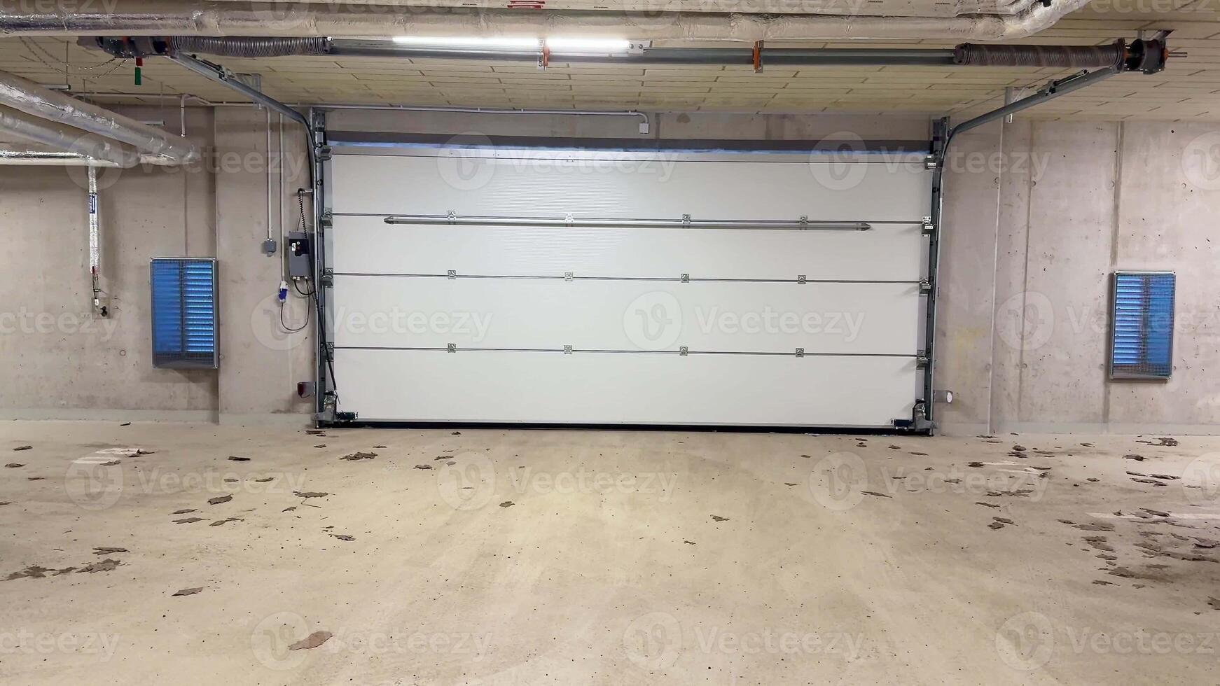 A wellorganized and clean garage space that features a stylish modern white garage door along with concrete walls photo