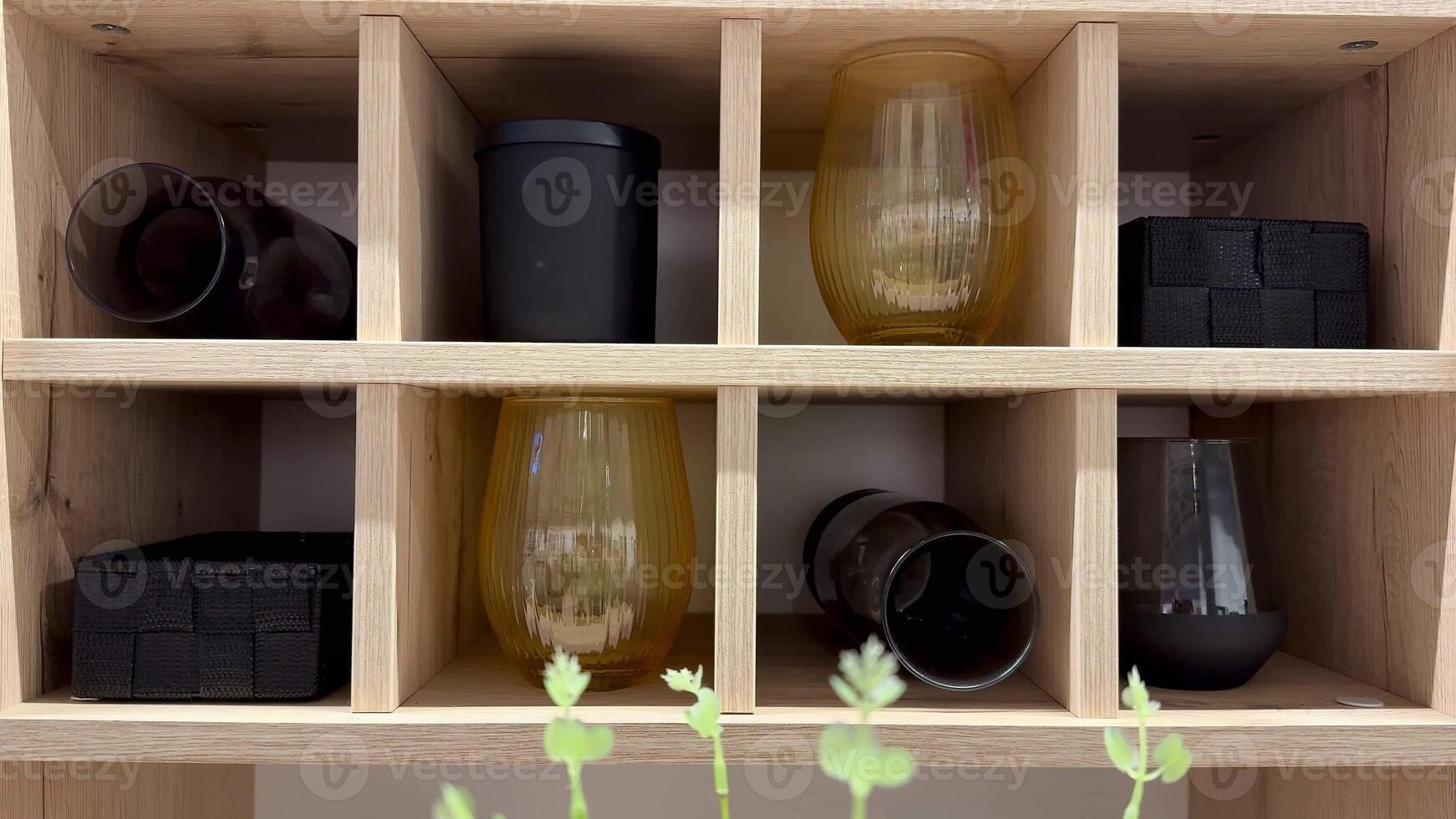 The beautiful display features a variety of elegantly arranged glasses and containers neatly placed on a wooden shelf photo