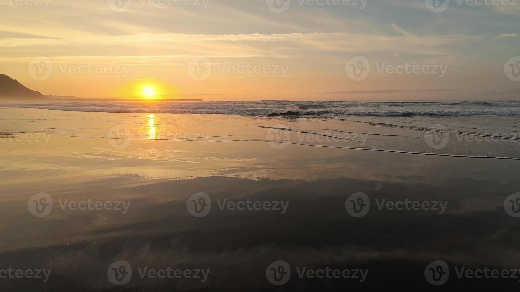 A breathtaking sunset casts its colors on the tranquil beach waters, creating a beautifully peaceful coastal vista photo