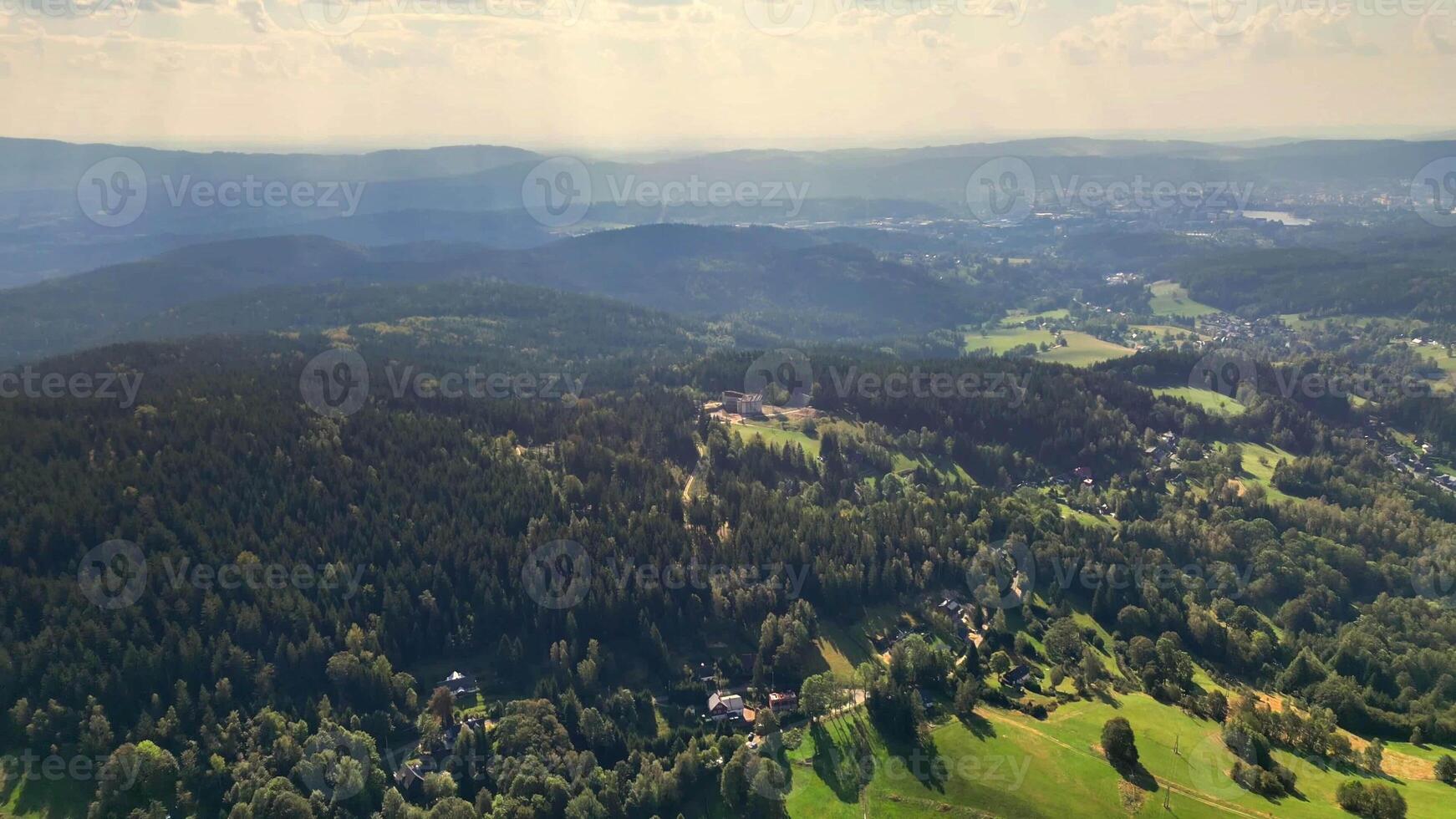 A breathtaking aerial shot that beautifully showcases expansive green forests and valleys beneath a clear sky photo