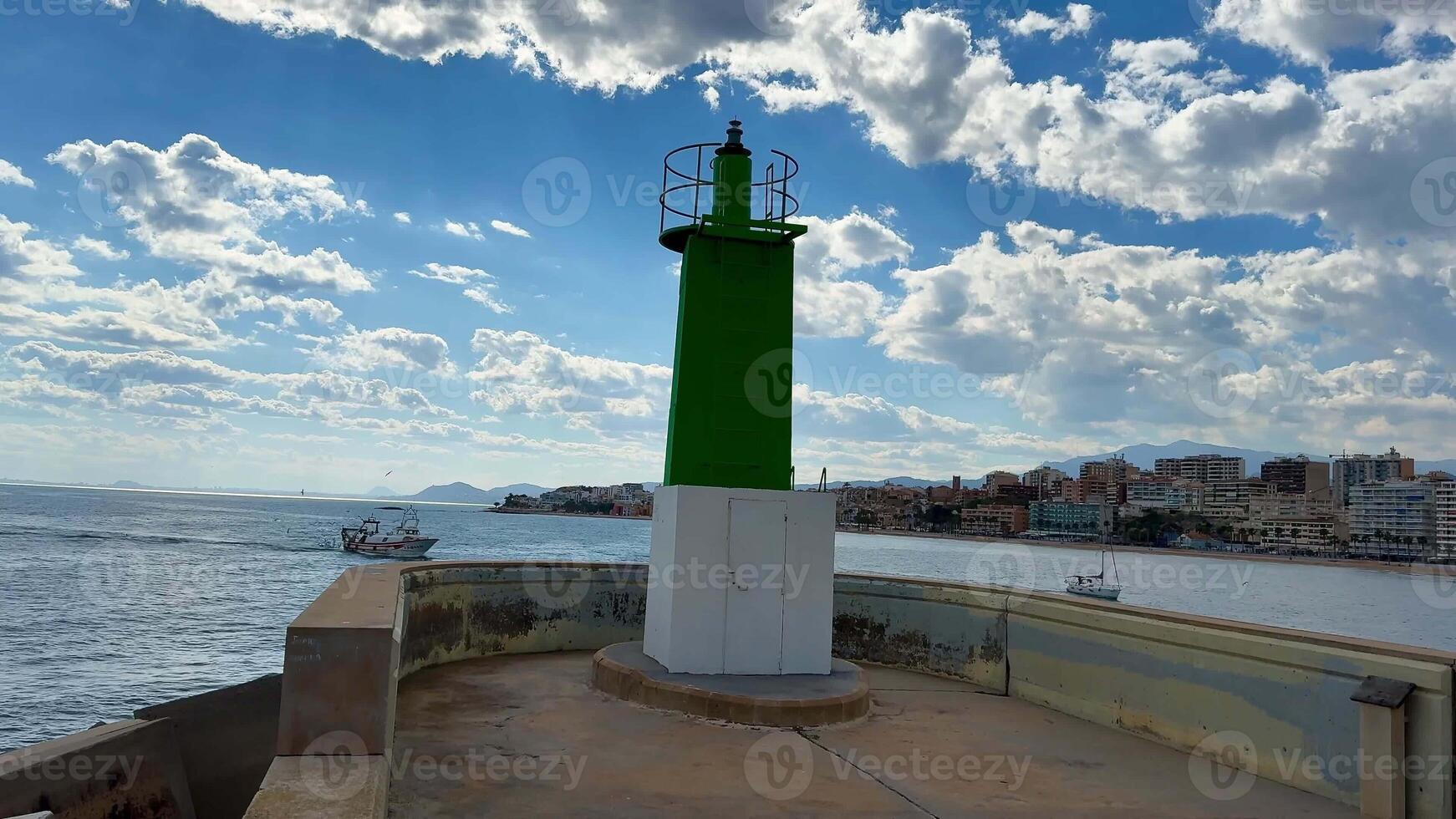 A vibrant, brilliantly green lighthouse majestically stands by the sea beneath a dramatic, cloudy sky overhead photo
