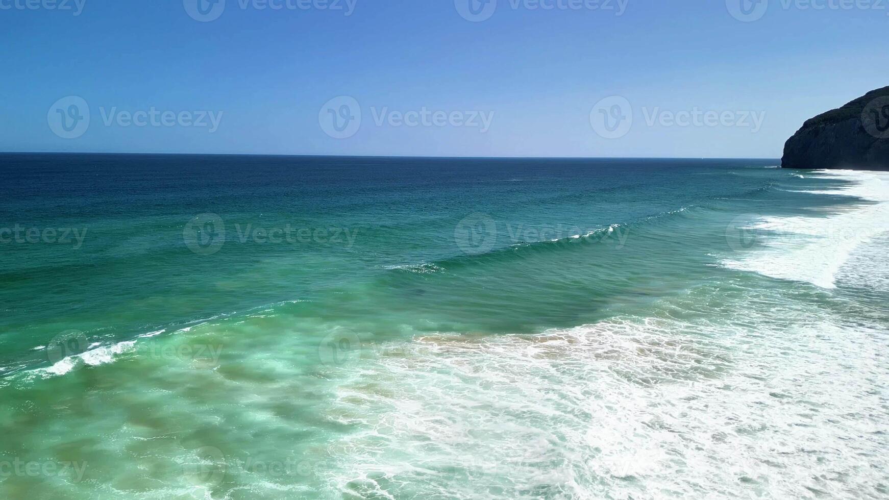 A breathtakingly beautiful view of a stunning beach featuring azure waves and people joyfully enjoying the warm sun photo