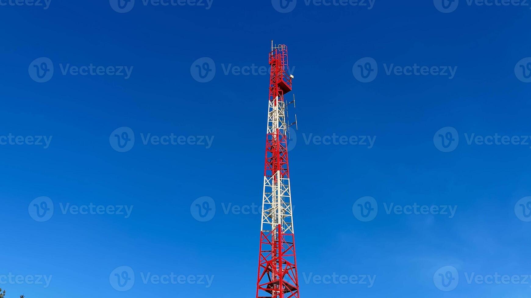 A tall and sturdy telecom tower representing modern communication technology set against a bright blue sky photo