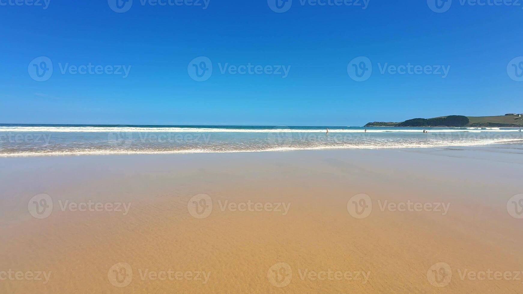 A beautiful and picturesque beach scene featuring soft sand, clear turquoise water, and an incredibly vivid blue sky photo