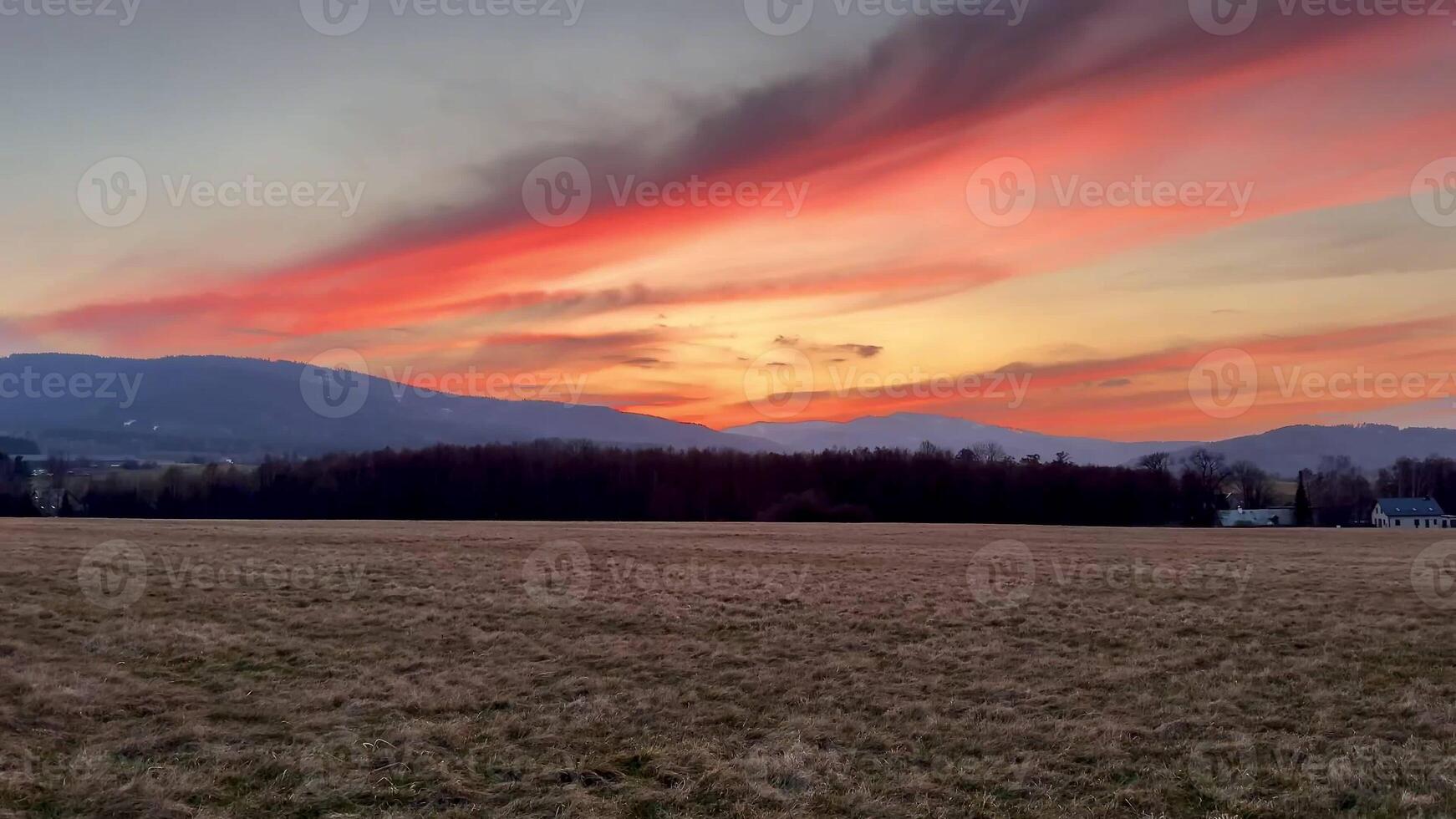 A breathtaking sunset vividly illuminating the expansive sky with vibrant hues over a serene landscape photo