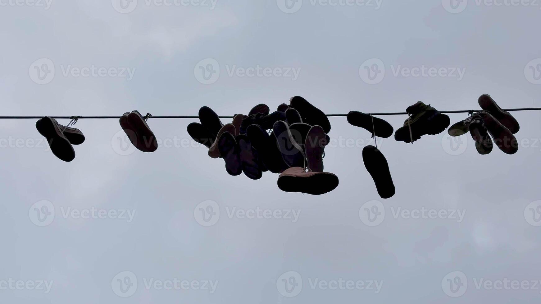 A vibrant cluster of shoes elegantly suspended from a wire against a moody, cloudy sky, representing urban culture photo