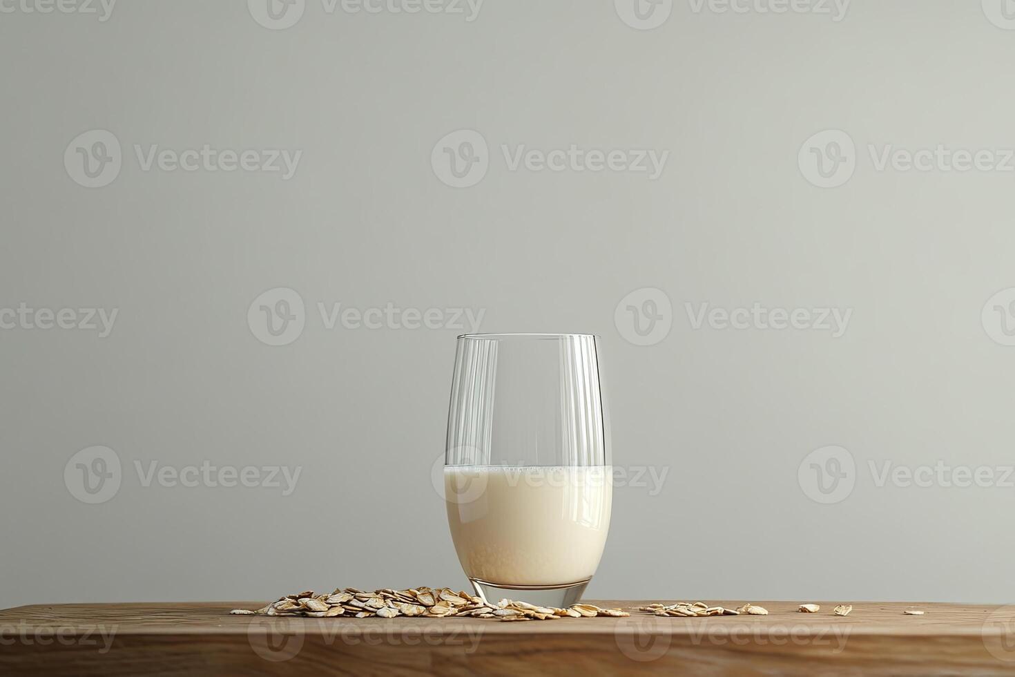 Oat milk in a glass with oats nearby on a wooden surface photo