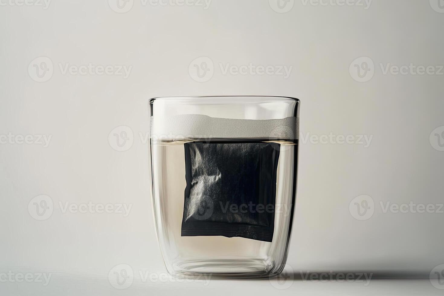 A Black Tea Bag Submerged In A Glass Of Water photo