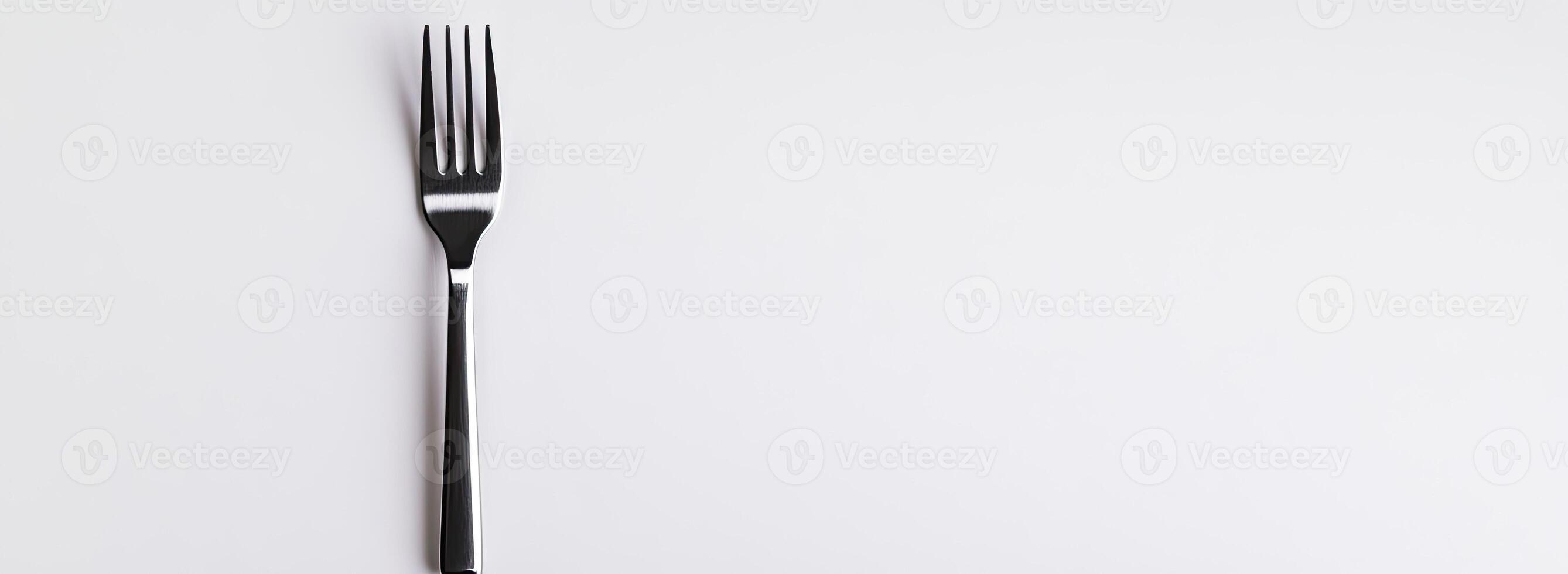 A single silver fork rests on a white background photo