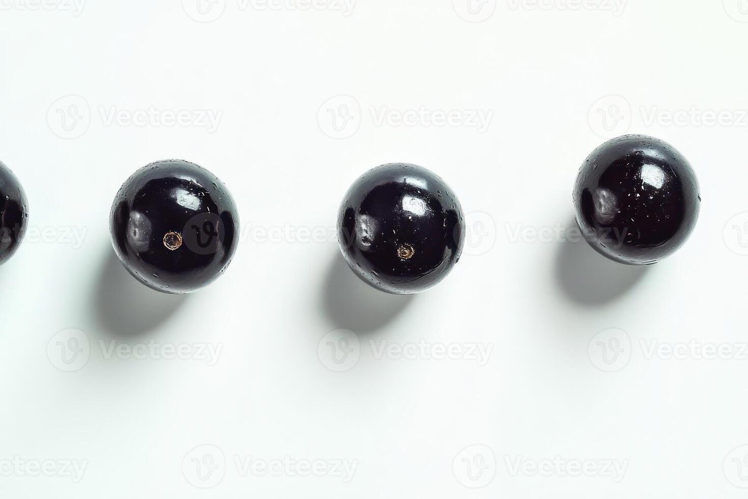 Three dark glistening jabuticabas arranged in a row photo