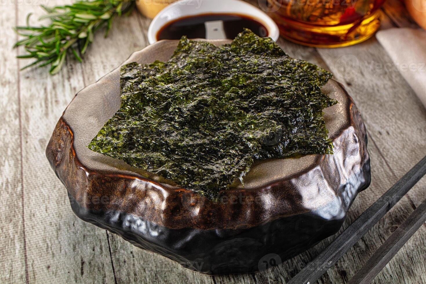 A bowl of seaweed with chopsticks and a bottle of whiskey photo