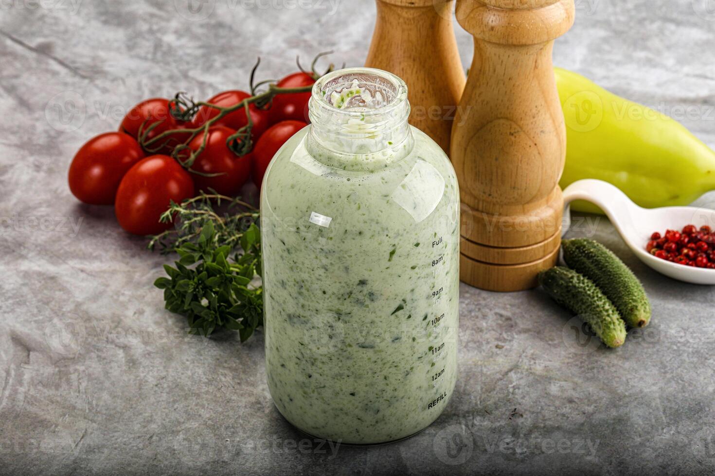 A bottle of dressing next to a pepper and a tomato photo
