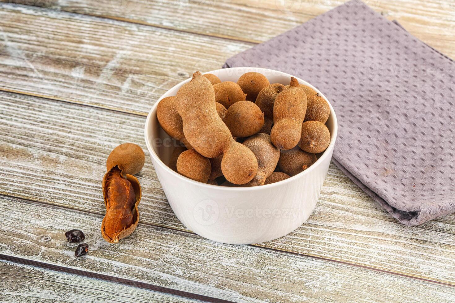 A bowl filled with nuts and a napkin on a wooden table photo