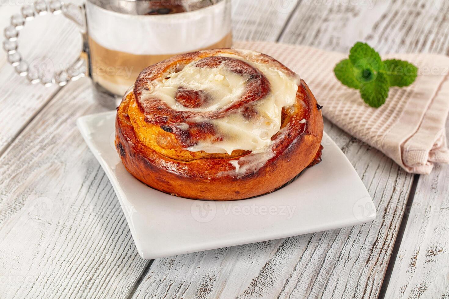 A cinnamon roll with cream cheese frosting on a white plate photo
