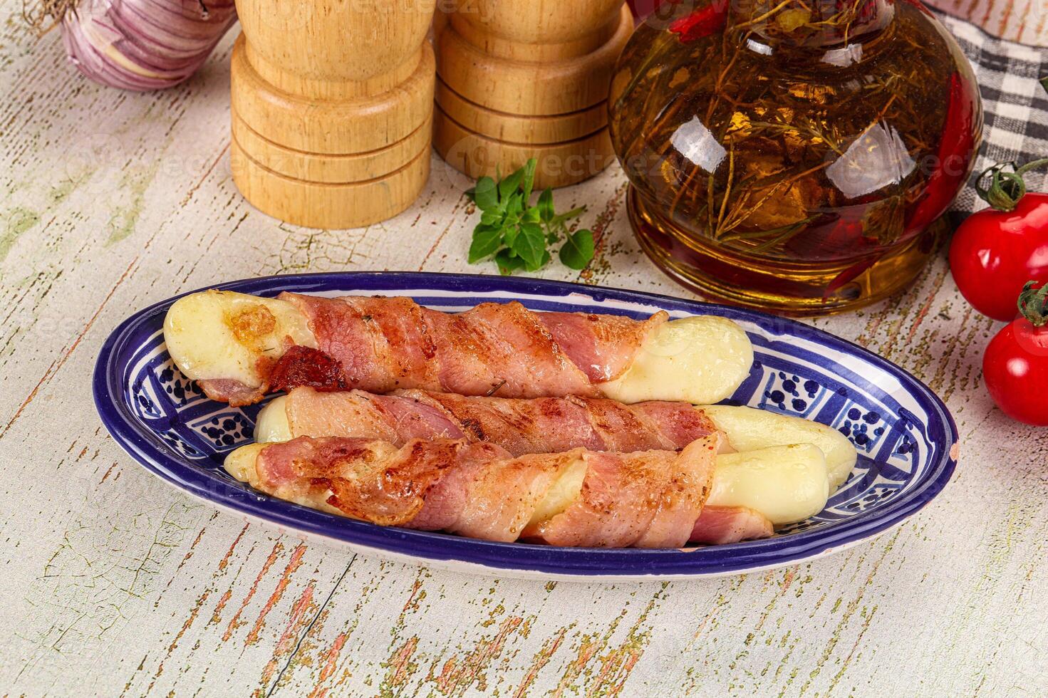 A plate with bacon wrapped potatoes and a bottle of olive oil photo