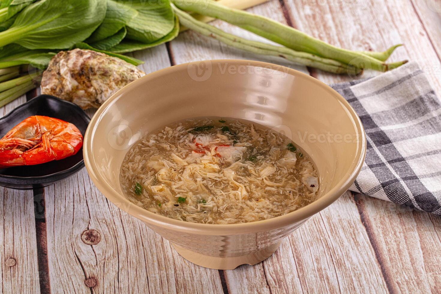 A bowl of soup on a table with vegetables photo