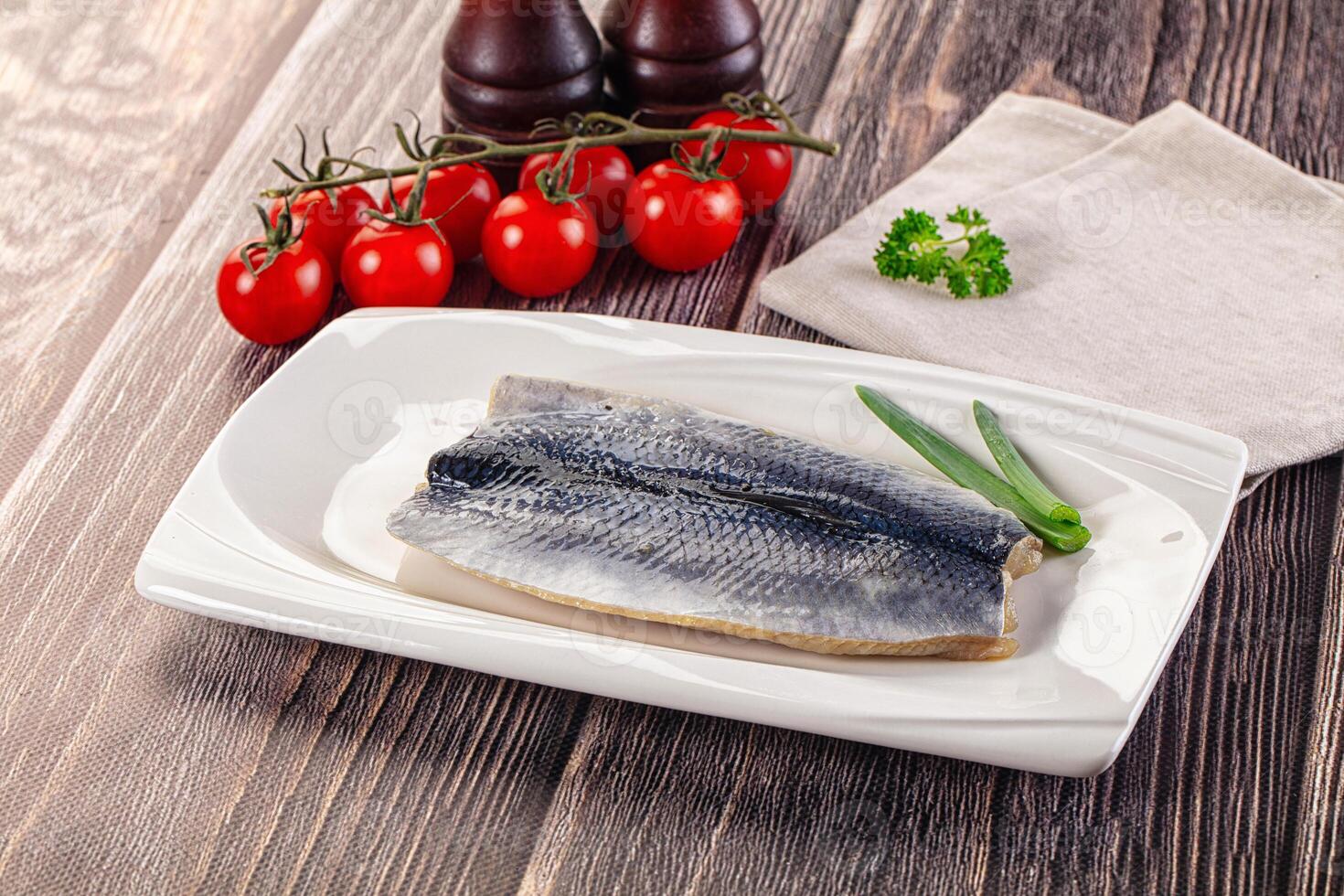 A piece of fish on a white plate with tomatoes and a bottle of wine photo