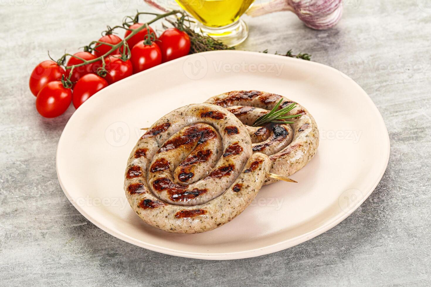 Two grilled sausages on a plate with tomatoes and olive oil photo
