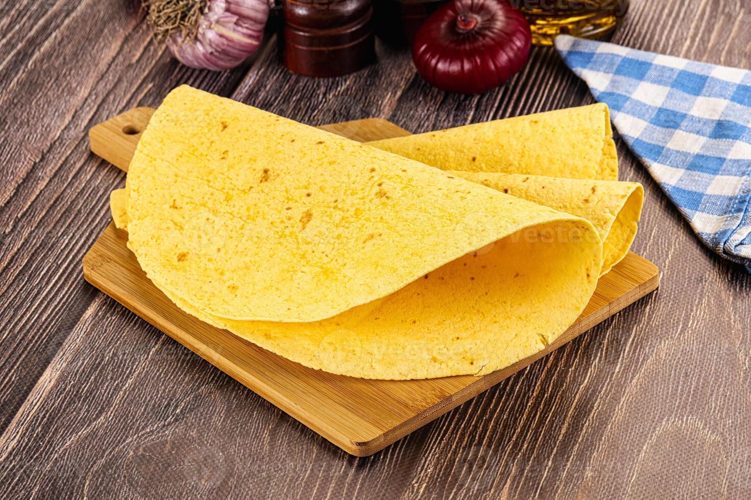 A tortilla on a cutting board next to a bottle of olive oil photo