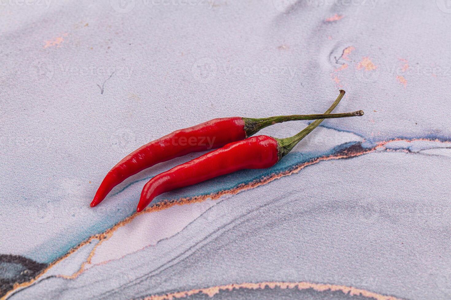 Two red chili peppers on a blue and white marble surface photo