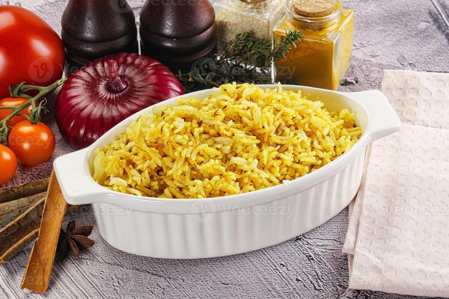 A bowl of yellow rice with spices and tomatoes photo