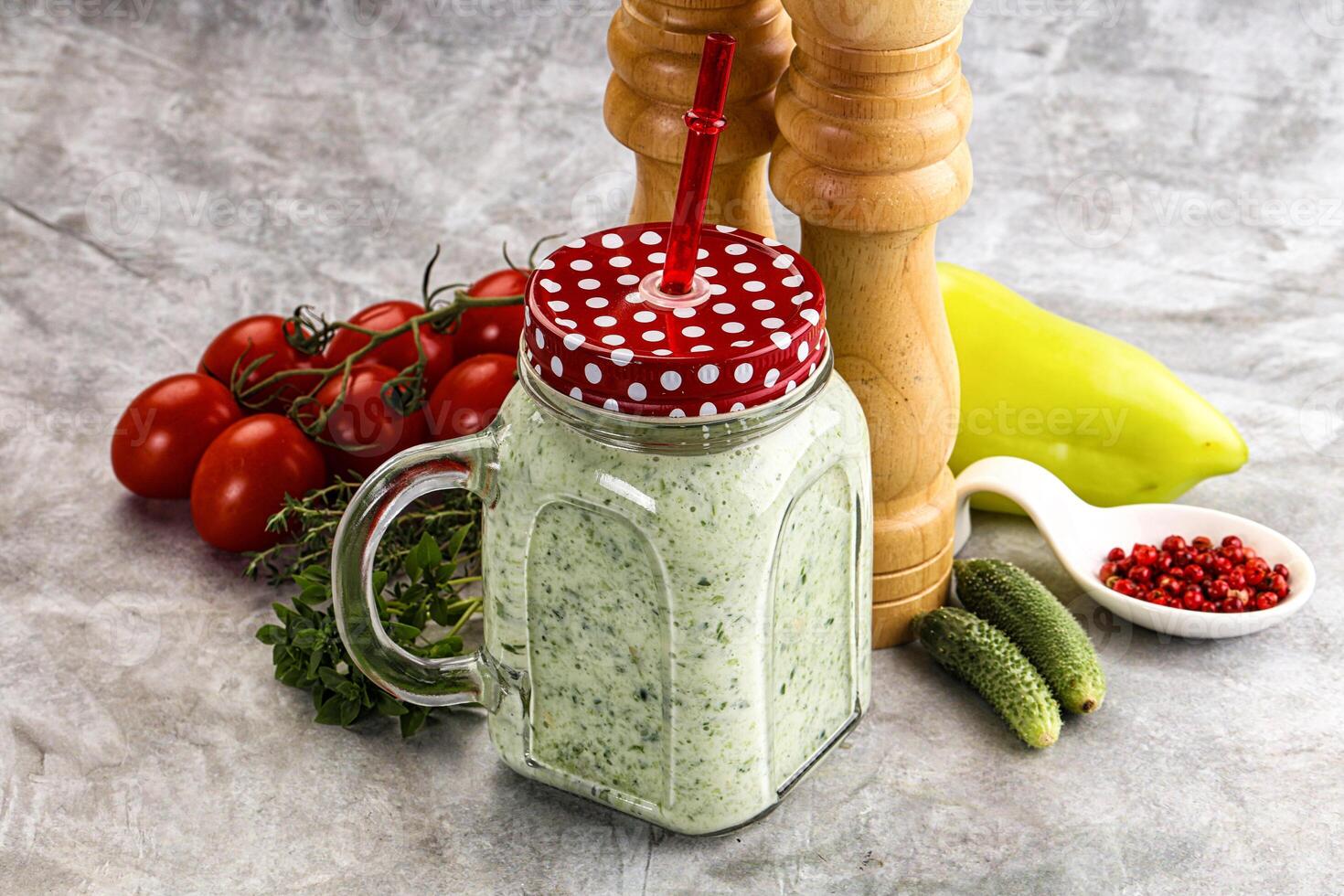 A jar of green smoothie with a red polka dot straw photo