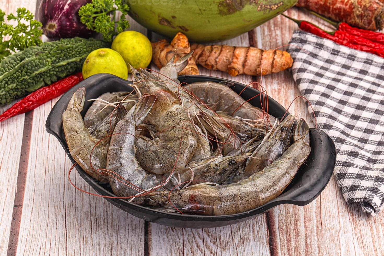 A bowl of shrimp sitting on a table next to a bowl of vegetables photo