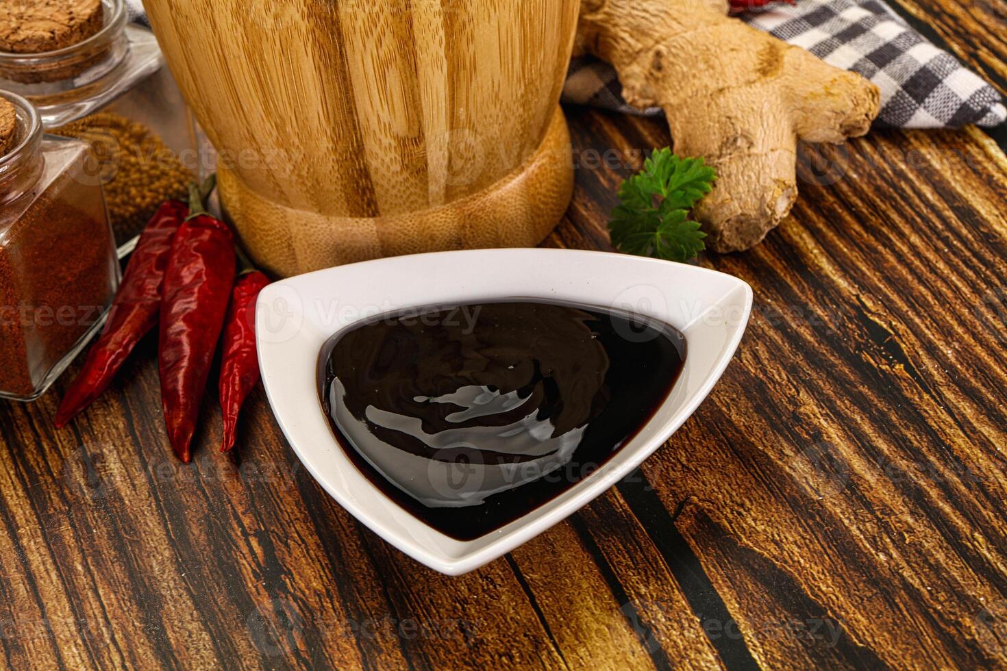 A wooden table with a bowl of sauce, spices and ginger photo