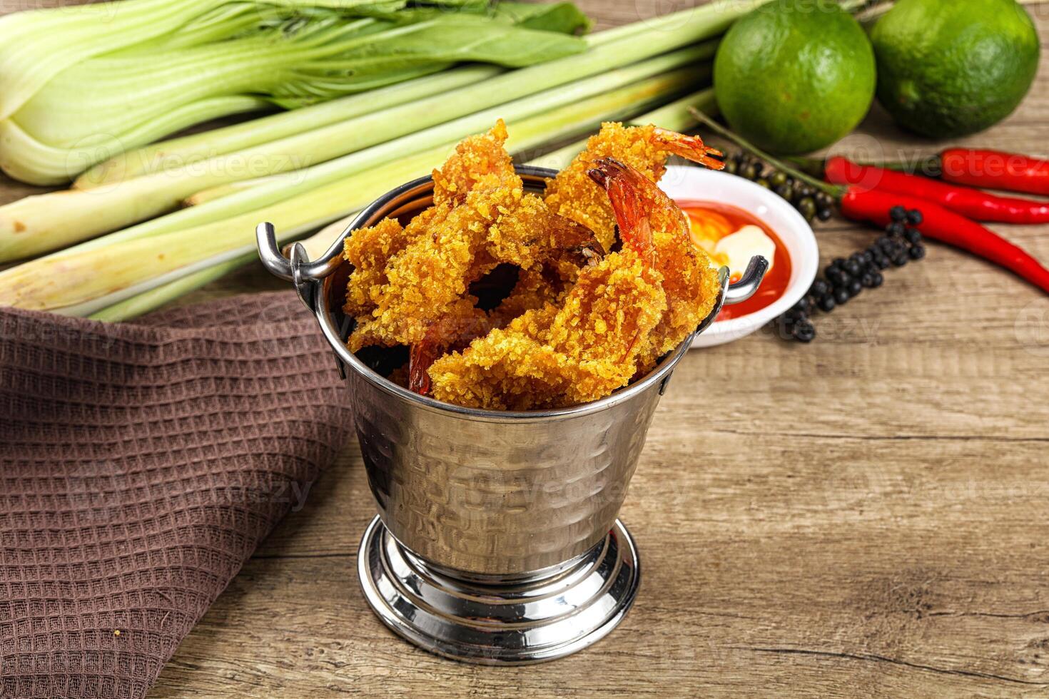 A silver cup filled with fried shrimp and other vegetables photo