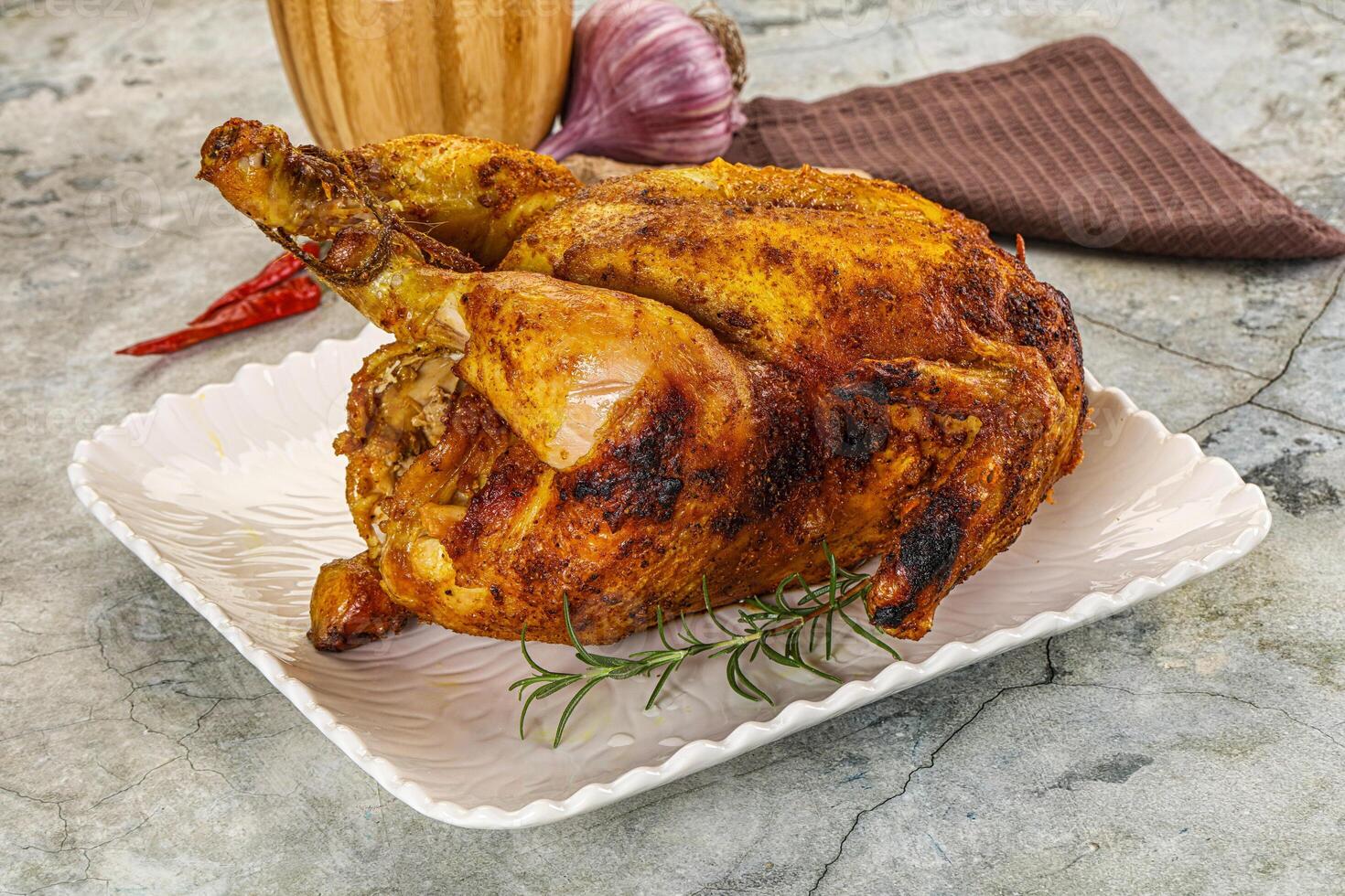 A roasted chicken on a plate with a glass of wine photo