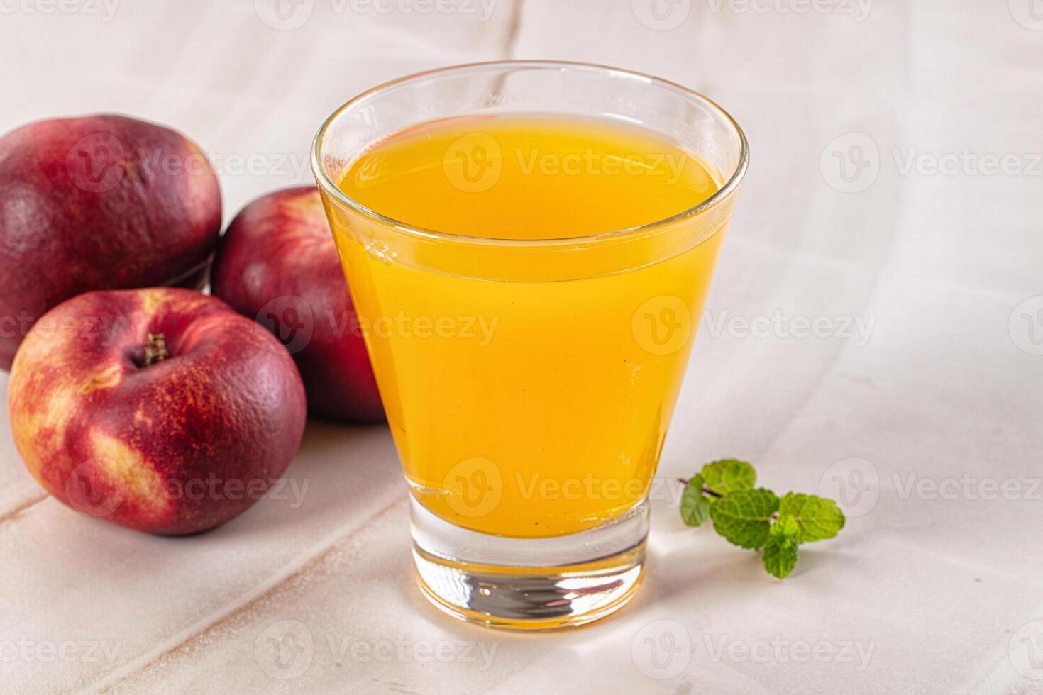 A glass of juice next to a bunch of peaches photo
