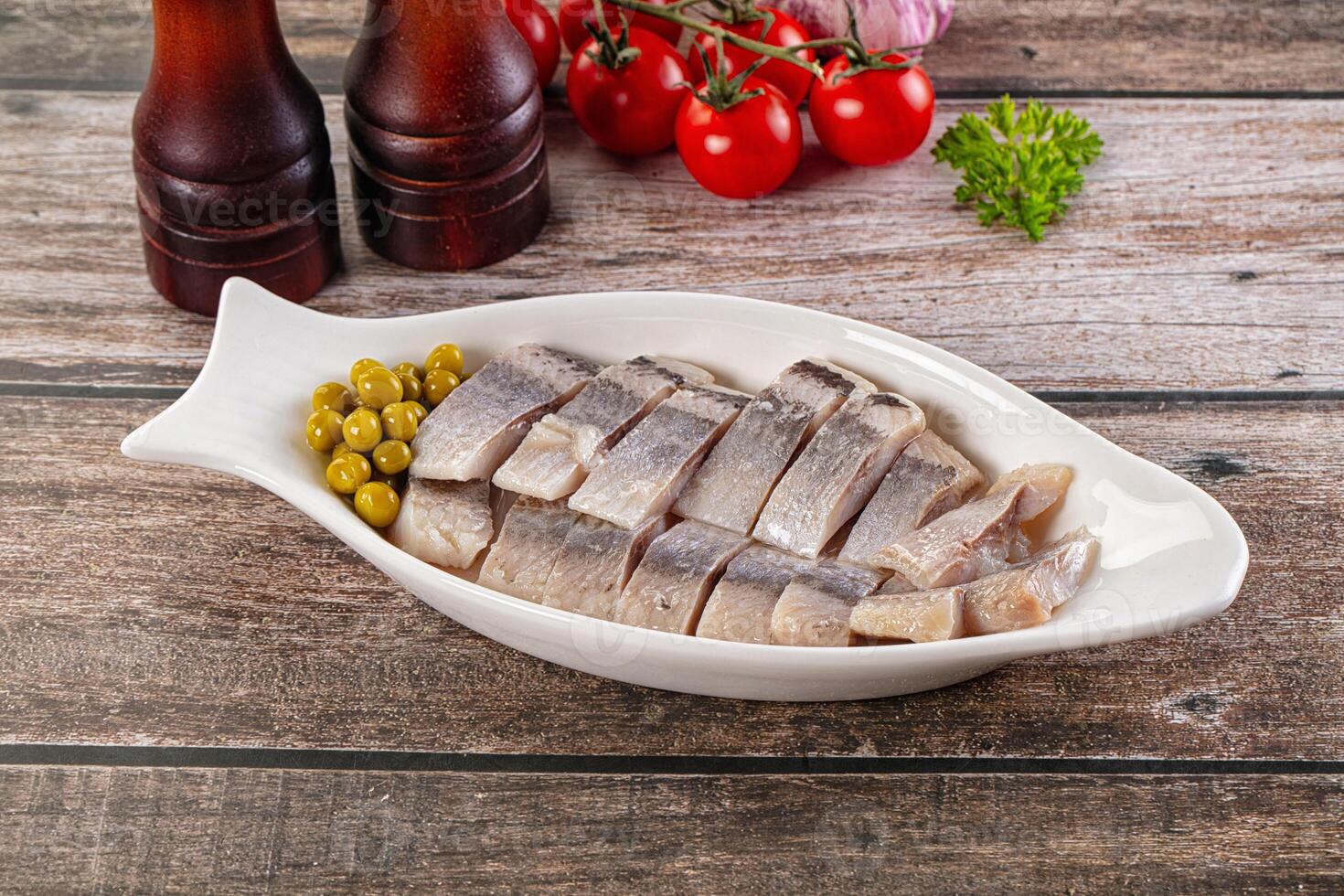 A white dish with sliced fish on top of a wooden table photo