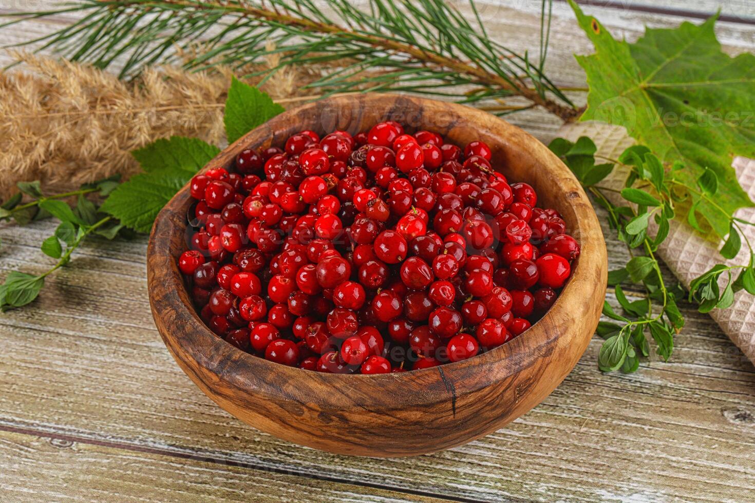 Red currant berries in a wooden bowl on a rustic wooden table photo