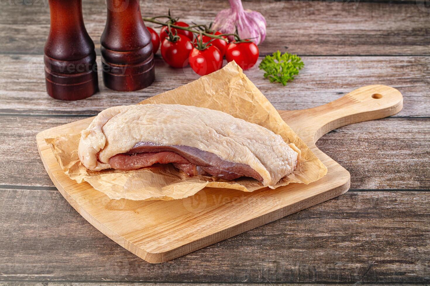 A piece of meat on a cutting board with a knife and a bottle of ketchup photo